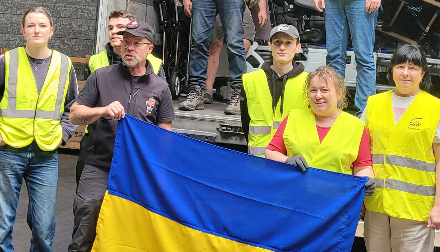 Bénévoles en gilets jaunes avec un drapeau ukrainien lors du chargement d’une aide humanitaire pour l’Ukraine