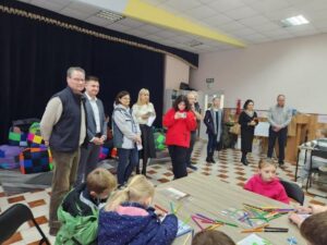Дорослі гості розмовляють у залі, де діти малюють за столом