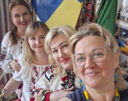 Quatre bénévoles en chemise brodée font un selfie devant le drapeau ukrainien du stand