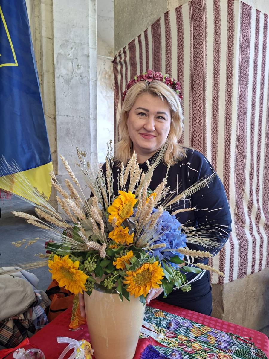 Bénévole d’Ukraine-Lorraine avec un bouquet de tournesols et d’épis de blé au stand de l’association